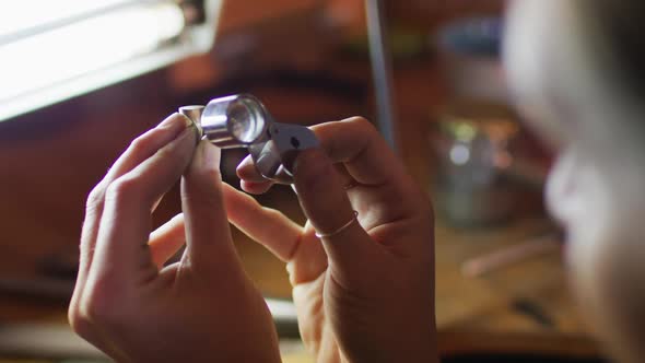 Close up of hands of caucasian female jeweller making jewelry in workshop