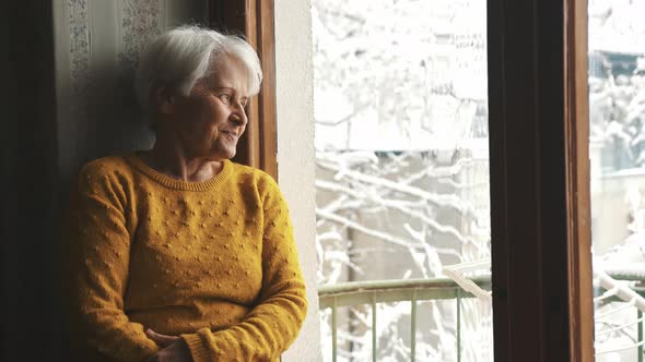 Pleasant Looking Senior Caucasian Woman Looking Out Through the Window and Thinking Medium Shot