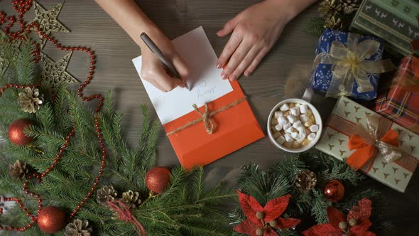 A Woman's Hands Writing a Christmas Card with a Pen