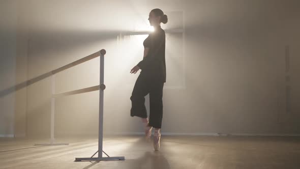 Wide Shot of Confident Slim Ballerina in Pointes Walking on Tiptoes to Barre in Backlit Fog