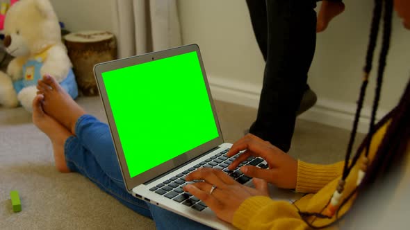 Side view of young black woman using laptop and sitting on floor of comfortable home 4k