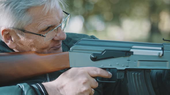 Elderly Gray Haired Man Holding a Gun in His Hands. War or Revolution Concept