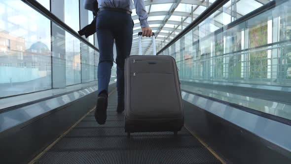 Legs of Successful Businessman Running in Hall of Terminal and Pulling Suitcase on Wheels