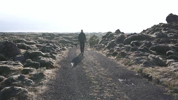 Traveler walking along road in rocky terrain
