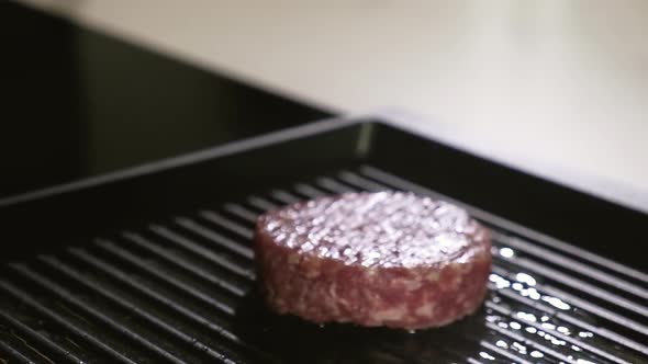 Chef puts raw meat for burger grill pan. Cooking delicious grilled hamburger