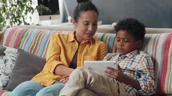 Afro Boy Using Tablet and Chatting with Mom on Sofa at Home