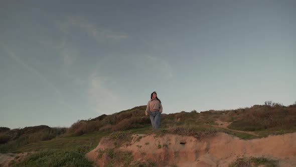 Traveling woman standing on hill at sunset