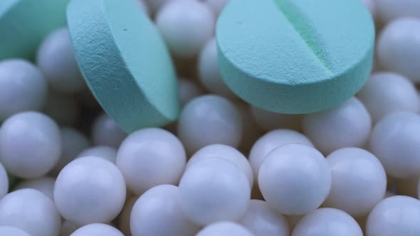 Round Green Medicines Lie on Scattered Small White Granules. Closeup Rotate alt