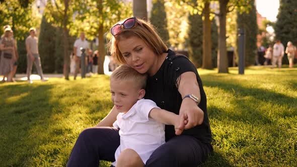 A Cheerful Mother with Her Little Eightyearold Son are Having Fun in a Park