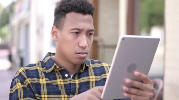 Young African Man Reacting to Loss on Tablet Outdoor