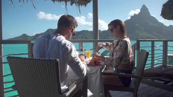 A man and woman couple eating breakfast outside at a tropical island resort