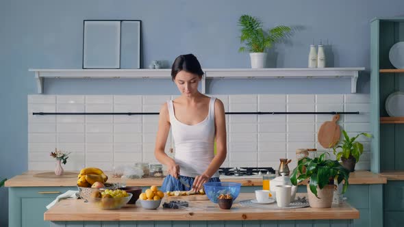 Young Woman Cutting Pear For Fruit Salad In The Morning