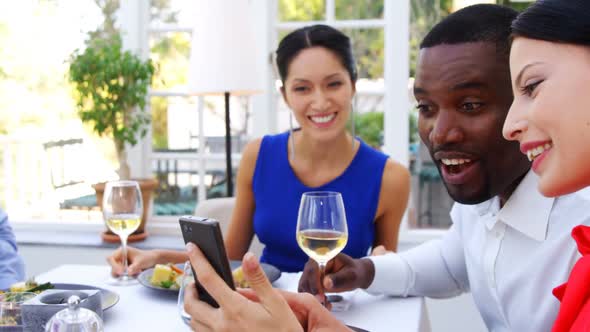 Friends using mobile phone while having meal