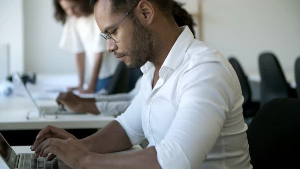 Focused Male Worker Typing on Laptop.