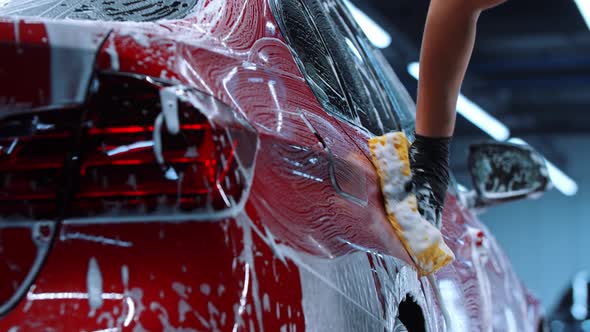 Auto Detailing  Man Washing a Red Car with a Cleaning Foam and a Big Sponge