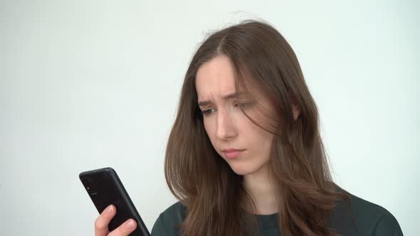 A Young Woman Emotionally Reading Messages on Her Smartphone