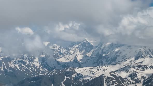 Air Flight Through Mountain Clouds Over Beautiful Snowcapped Peaks of Mountains and Glaciers