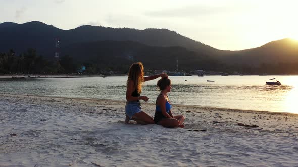 Modern smiling girls travelling by the sea on beach on clean white sand and blue background 