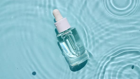 Glass Cosmetic Bottle with Pipette Lies on the Surface of the Water