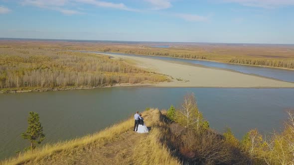 Couple Stands on Steep River Bank on Autumn Day Aerial View