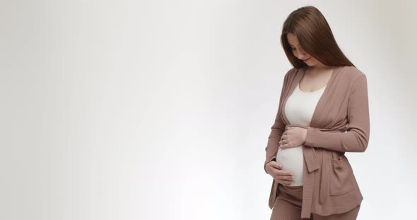 Happy Young Pregnant Woman Stroking Her Big Belly White Studio Background with Empty Space