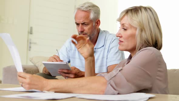 Stressed couple working out their finances on the couch