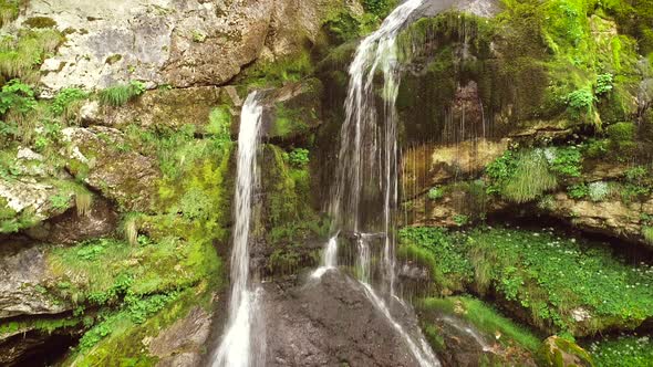 Aerial view of a waterfall surrounded by rocks and nature nearby Soca River.