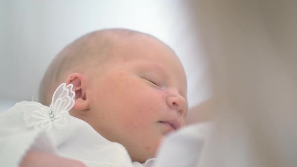 Newborn baby girl asleep in her mothers arms