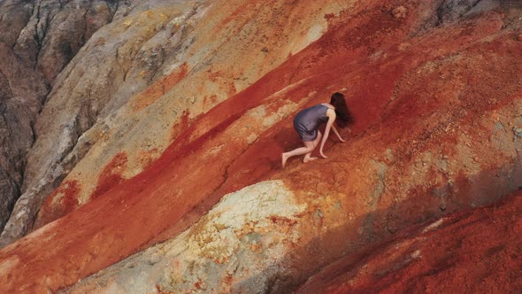 Aerial View of a Girl Who Climbs the Red Mountains in a Dress