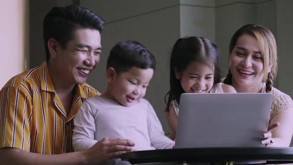 Happy family with kids enjoying using application on laptop together at home