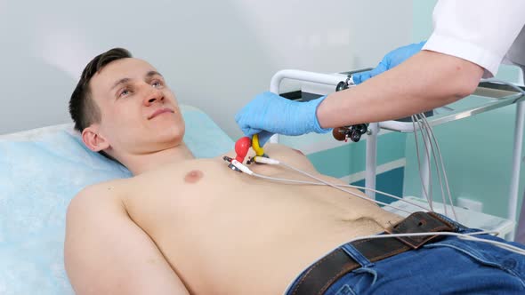 Nurse Puts Electrodes on Man Patient to Do Electrocardiogram