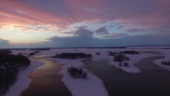 Stunning sunset making clouds purple viewed by flying drone in winter scenery