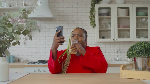 Lovely Black Female Networking with Phone Indoors