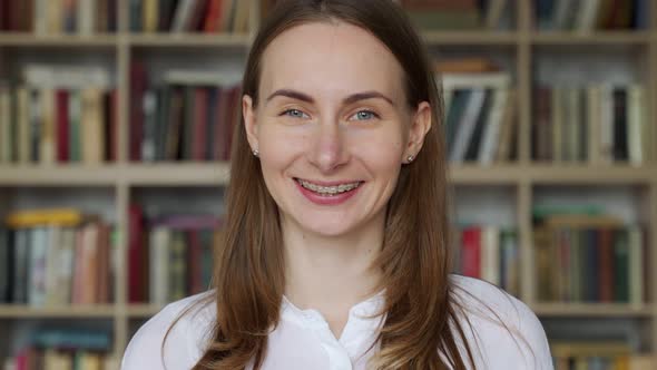 Portrait of a Young Woman with Braces on Her Teeth Smiling Looking at the Camera Against the