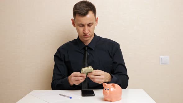 Young Man Holds Dollar Banknotes Writing Family Expenses