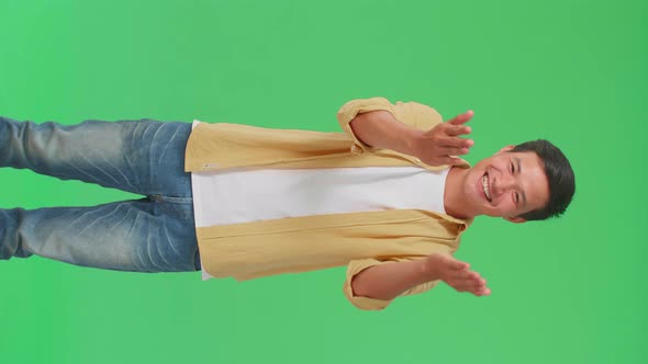 Portrait Of A Smiling Asian Man Blowing Kisses To A Camera In The Green Screen Studio