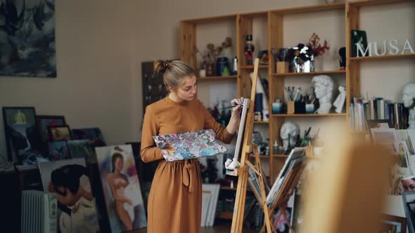 Creative Young Lady Is Painting with Oil Paints Working in Studio Alone Standing in Front of Easel