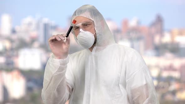 Man Wearing Protective Suit and Observing Blood Test Tube