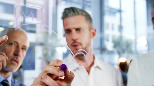 Business colleagues talking while writing on glass window