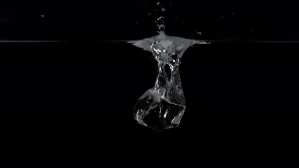Ice cube dropped into water against black background. Slow Motion. alt