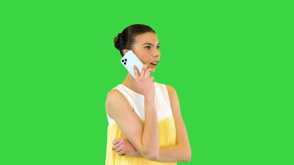Young Beautiful Girl in Whiteyellow Dress Stands Talking on Mobile Phone and Smiles on a Green