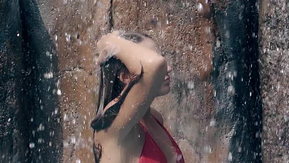 Slim Woman with Long Hair Relaxes Under Artificial Waterfall