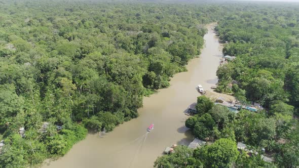 Aerial shot following boat on amazonian river inside jungle (Para, Brazil)