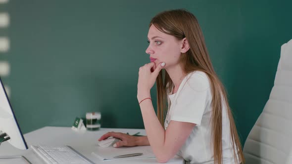 Caucasian Woman Working in Office Sitting at the Table and Looking at the Monitor