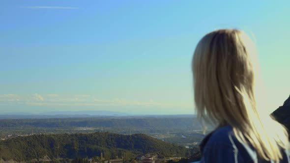 free, happy female traveler in denim jacket, looking into distance at mountains