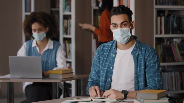 Young Clever Guy Student in Protective Mask Writes Notes Prepares for Exam Makes Project Writing