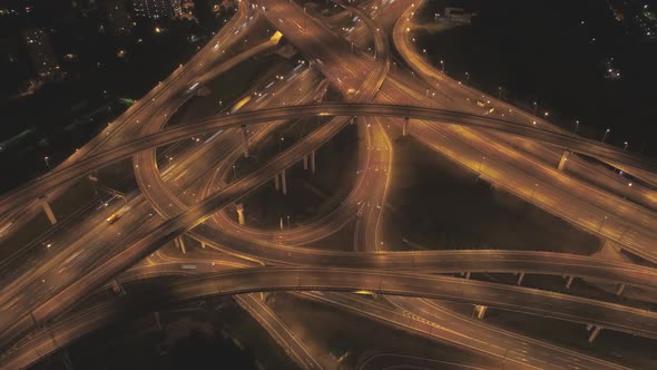 Illuminated Complex Road Junction and Cars Traffic at Night. Drone Is Orbiting Around. Aerial View