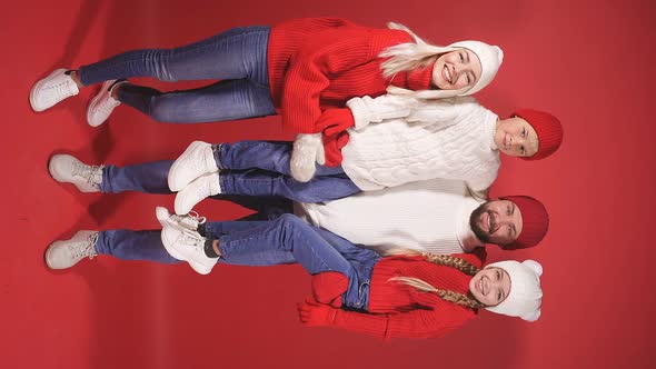Young Caucasian Family in Sweaters, Isolated on Red Wall Background.