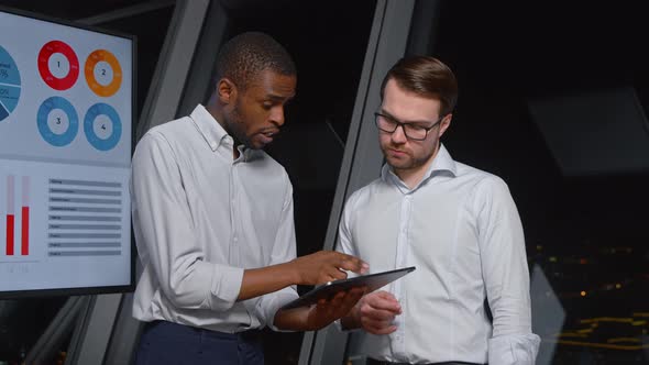 Serious corporate managers of different ethnicity discussing business strategy using digital tablet