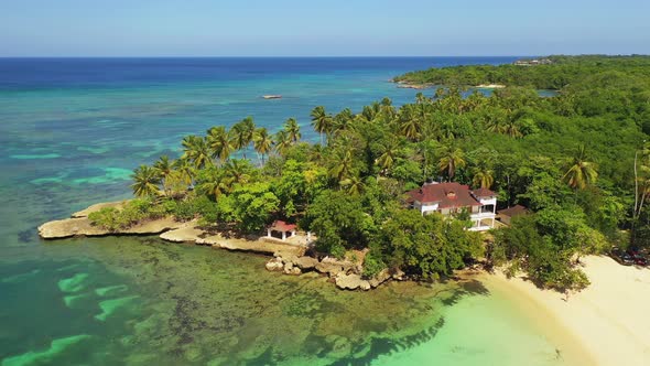 Tropical resort travel destination with green lush palm trees on rocky coastline with crystal clear